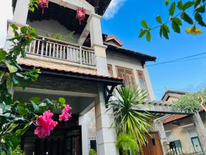 順化的住宿－武三維恩民宿，带阳台和粉红色鲜花的房子