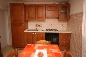 a kitchen with wooden cabinets and a table and a sink at Apartments by the sea Zambratija, Umag - 7030 in Zambratija