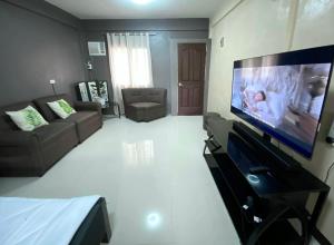 sala de estar con TV de pantalla plana grande en Adam's Hotel Apartment en Pandi