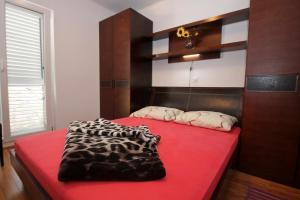 een slaapkamer met een rood bed en een luipaarddeken bij Apartments with WiFi Cavtat, Dubrovnik - 9063 in Cavtat