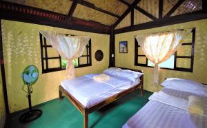 twee bedden in een kamer met twee ramen bij Concepcion Divers Lodge in Busuanga