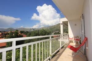 een balkon met een rode stoel en uitzicht op de bergen bij Apartments with WiFi Cavtat, Dubrovnik - 9063 in Cavtat