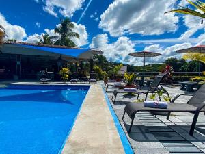 a swimming pool with chairs and umbrellas on a resort at Hotel El Regalo in Nicoya