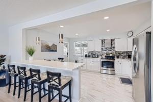 a kitchen with white cabinets and a large island with chairs at Private House Near DT Denver & Mountains, Pet Friendly, Fire Pit, Ping Pong Table, Explore or Relax at this Arvada Retreat in Arvada