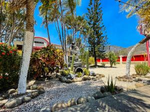 a garden with rocks and palm trees and a building at Hotel El Regalo in Nicoya