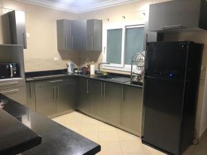 een keuken met zwarte kasten en een zwarte koelkast bij Serviced apartment -Sheraton Al Matar (Ocean blue) in Caïro