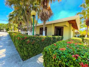 a yellow building with flowers and palm trees at Hotel El Regalo in Nicoya +8 photos