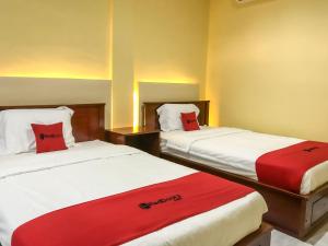 2 bedden in een hotelkamer met rode kussens bij RedDoorz @ Gerson Hotel Abepura in Tobadi