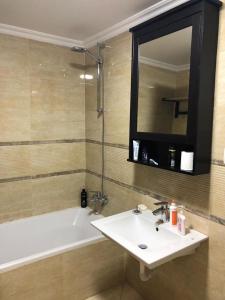 ein Badezimmer mit einem Waschbecken, einer Badewanne und einem Spiegel in der Unterkunft Serviced apartment -Sheraton Al Matar (Ocean blue) in Kairo