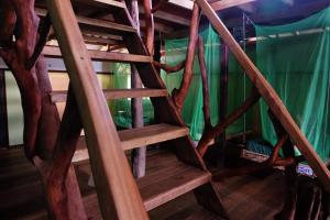 a wooden spiral staircase in a room with green curtains at The Kasbah Langkawi in Pantai Cenang