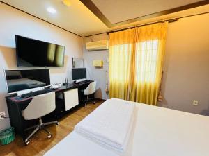 1 dormitorio con escritorio, ordenador y cama en Sweet Hotel, en Jeju
