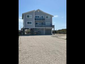 a large house sitting on top of a gravel driveway at Somewhere South home in Holden Beach