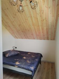 uma cama num quarto com tecto em madeira em Domek u Antosia em Mechelinki