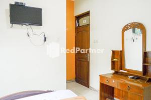 een slaapkamer met een spiegel en een dressoir bij PKPN Syariah Boyolali Mitra RedDoorz in Mojosongo