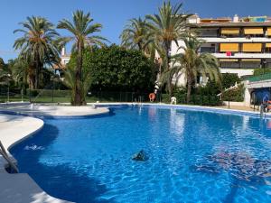 une grande piscine bleue avec des palmiers et un bâtiment dans l'établissement Golden Mile Apartment, à Marbella