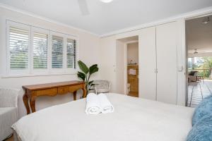 a white bedroom with a bed and a desk at Summer Salt in Byron Bay