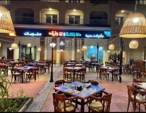 ein leeres Restaurant mit Tischen, Stühlen und Lichtern in der Unterkunft اكوا فيو الساحل الشمالى - مصريين فقط in El-Alamein