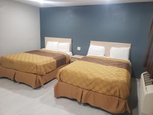 2 camas en una habitación con paredes azules en Village Inn Cotulla, en Cotulla
