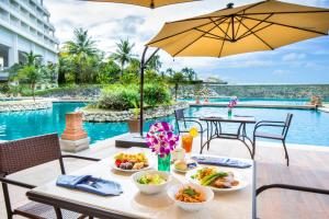 stół z jedzeniem i parasol obok basenu w obiekcie RIHGA Royal Laguna Guam Resort w Tamuning
