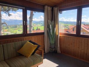 um quarto com um sofá e uma janela com um vaso de flores em PanoramaApart - Alpzeit im Westallgäu em Oberreute