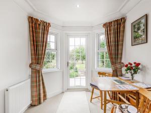 a dining room with a table and two windows at Ralston Bothy in Blairgowrie