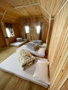 a room with four beds in a wooden room at Chimney Farmstay in Kurseong