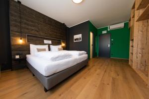a bedroom with a large bed and green walls at Self-Check-in Hotel VinoQ Zistersdorf in Zistersdorf