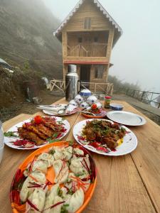 un tavolo in legno con piatti di cibo sopra di Chimney Farmstay a Kurseong