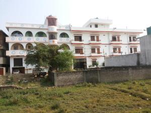 ein großes weißes Gebäude mit einem Baum davor in der Unterkunft Suma Guest House in Bodh Gaya