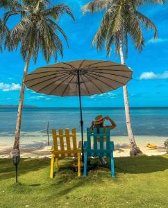 Buruanga的住宿－Tuburan Cove Beach Resort，海滩上两把椅子放在伞下