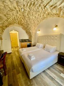 a bedroom with a large white bed in a stone wall at Petrakis Inn in Jerusalem