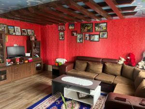 sala de estar con sofá y pared roja en The North Face Inn's Homestay en Pokhara