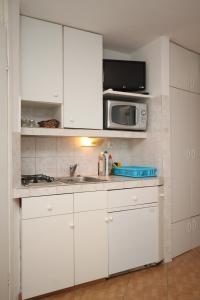 a white kitchen with a sink and a microwave at Studio Basanija 7148a in Savudrija
