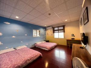 - 2 lits dans une chambre avec des nuages peints sur le mur dans l'établissement Golden flower Homestay, à Yuli
