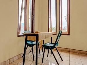 - une table et deux chaises dans une chambre avec fenêtres dans l'établissement OYO 91636 Kak Dadut Homestay, à Batam Center