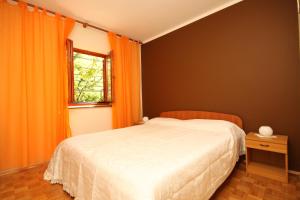 1 dormitorio con cama de color naranja y ventana en Apartments with a parking space Fazana - 7153 en Fažana