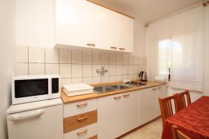 a kitchen with white cabinets and a microwave at Apartments with parking space Fazana - 7153 in Fažana