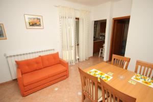 a living room with an orange couch and a table at Family friendly apartments with a swimming pool Lindar, Central Istria - Sredisnja Istra - 7197 in Pazin