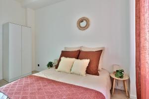 Schlafzimmer mit einem Bett mit roten und weißen Kissen in der Unterkunft Appartement Cosy Bourgoin - Gare & Centre in Bourgoin