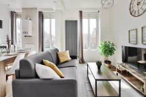 ein Wohnzimmer mit einem grauen Sofa und einem Tisch in der Unterkunft Appartement Cosy Bourgoin - Gare & Centre in Bourgoin