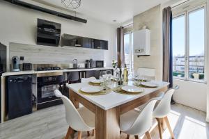 eine Küche mit einem Tisch mit weißen Stühlen und einem Esszimmer in der Unterkunft Appartement Cosy Bourgoin - Gare & Centre in Bourgoin