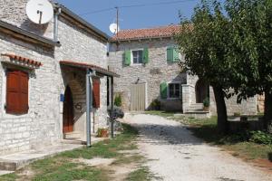 an old stone house with a tree and a driveway at Apartments with a parking space Heraki, Central Istria - Sredisnja Istra - 7167 in Stifanići