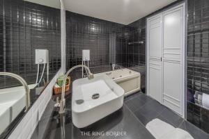 La salle de bains est pourvue de carrelage noir, d'un lavabo et d'une baignoire. dans l'établissement The Ring Border, à Ban Khlong Phruan