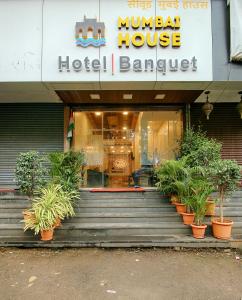 a hotel with potted plants in front of a building at Hotel Mumbai House Juhu, Santacruz West, Mumbai in Mumbai
