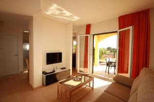 Una sala de estar con un sofá, una mesa y un televisor. en Residence Club Deluxe, en Sa Ràpita