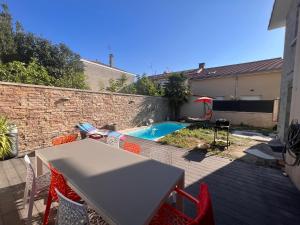 un patio con mesa y sillas y una piscina en Maison moderne et spacieuse avec piscine, en Villeurbanne
