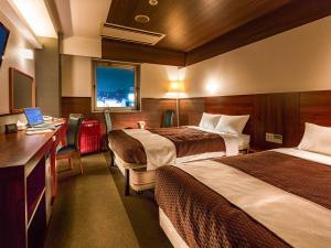 a hotel room with two beds and a desk with a laptop at Tokai City Hotel in Tokai