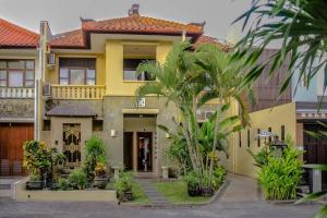 una casa amarilla con palmeras delante en 5 Bedroom Holiday Villa - Kuta Regency B8, en Kuta
