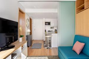 een woonkamer met een blauwe bank en een televisie bij JOIVY Bright Flat, Quiet Area in Porto