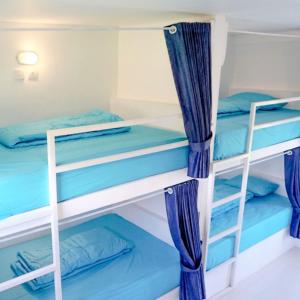 two bunk beds in a room with blue curtains at Swell Hotel, Pool Bar & Restaurant in Tanah Lot